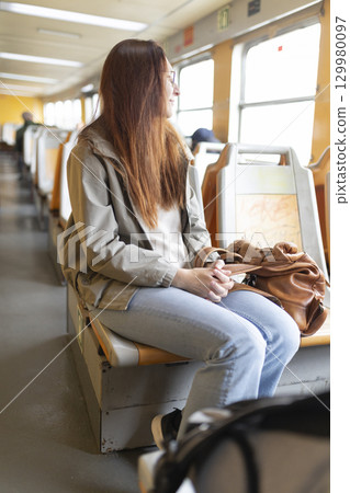 Young woman relaxing looking out train window during scenic journey 129980097