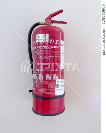 Red fire extinguisher mounted on a wall with clear instructions Red fire extinguisher mounted on a wall with clear instructions 129980909