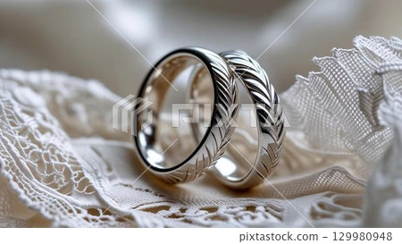 白色蕾絲上排列著結婚戒指的特寫鏡頭 白色蕾絲上排列著結婚戒指的特寫鏡頭 129980948
