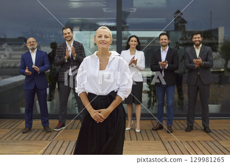 Confident female leader applauded by diverse business team on rooftop terrace Confident female leader applauded by diverse business team on rooftop terrace 129981265