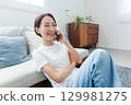 微笑的年輕女士在客廳打電話 129981275