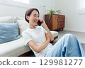 微笑的年輕女士在客廳打電話 129981277