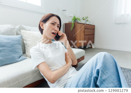 Young woman leaning on the sofa and making an angry phone call 129981279