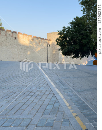 An old fortress stone wall and a cobbled street at dawn An old fortress stone wall and a cobbled street at dawn 129982321
