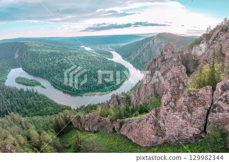 Stunning panoramic view of a winding river amidst lush green forests in a mountainous region during daylight. Rocks and the Mana River, the nature of the Siberian taiga 129982344
