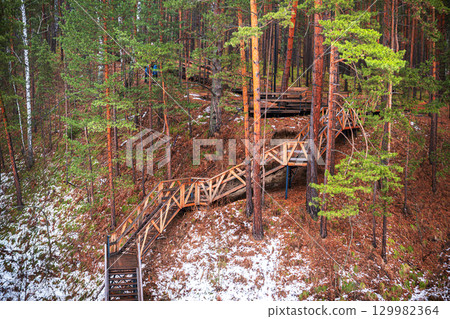 Stroll along winding wooden paths through an autumn forest in October with vibrant foliage and serene surroundings 129982364