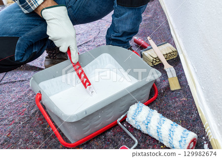 House painter worker prepares white paint. Building. House painter worker prepares white paint. Building. 129982674