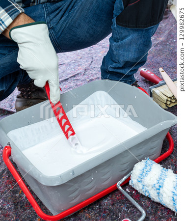 House painter worker prepares white paint. Building. 129982675