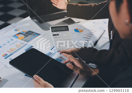 Focused young businessman signing agreement with skilled lawyer in eyeglasses. Concentrated financial advisor showing place for signature on paper contract document to male client at meeting in office 129983118