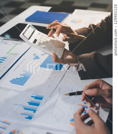 Focused young businessman signing agreement with skilled lawyer in eyeglasses. Concentrated financial advisor showing place for signature on paper contract document to male client at meeting in office 129983128