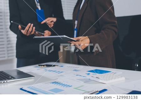 Focused young businessman signing agreement with skilled lawyer in eyeglasses. Concentrated financial advisor showing place for signature on paper contract document to male client at meeting in office 129983138