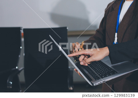 Focused young businessman signing agreement with skilled lawyer in eyeglasses. Concentrated financial advisor showing place for signature on paper contract document to male client at meeting in office 129983139