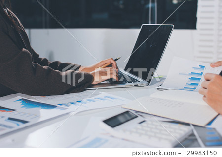 Focused young businessman signing agreement with skilled lawyer in eyeglasses. Concentrated financial advisor showing place for signature on paper contract document to male client at meeting in office 129983150