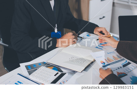 Focused young businessman signing agreement with skilled lawyer in eyeglasses. Concentrated financial advisor showing place for signature on paper contract document to male client at meeting in office Focused young businessman signing agreement with skilled lawyer in eyeglasses. Concentrated financial advisor showing place for signature on paper contract document to male client at meeting in office 129983151