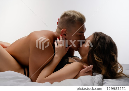 Couple shares an intimate moment in a cozy bedroom setting at sunset Couple shares an intimate moment in a cozy bedroom setting at sunset 129983251