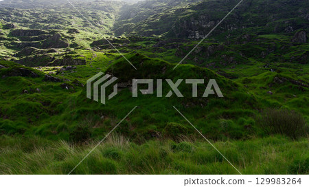 The Gap of Dunloe in County Kerry, Ireland, is a place where you can see lush green hills covered in grass. The Gap of Dunloe in County Kerry, Ireland, is a place where you can see lush green hills covered in grass. 129983264