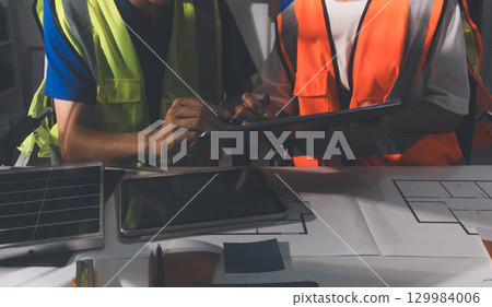 Closeup of team of industrial engineers meeting analyze machinery blueprints consult project on table in manufacturing factory. Working in manufacturing plant or production plant. Closeup of team of industrial engineers meeting analyze machinery blueprints consult project on table in manufacturing factory. Working in manufacturing plant or production plant. 129984006