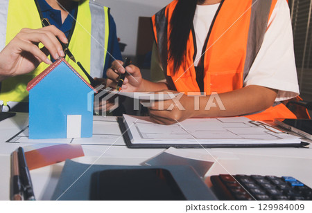 Closeup of team of industrial engineers meeting analyze machinery blueprints consult project on table in manufacturing factory. Working in manufacturing plant or production plant. 129984009