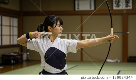 弓道部一名女成員正在註視目標 弓道部一名女成員正在註視目標 129984344