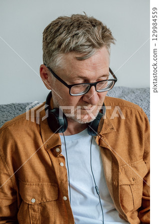 middle-aged man focused on task while wearing headphones in cozy indoor. closeup. 129984559