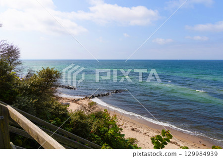 Sea shoreline with rocky breakwater and blue sky with clouds Sea shoreline with rocky breakwater and blue sky with clouds 129984939