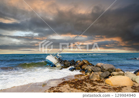 A broken yacht near the seashore in cloudy weather 129984940