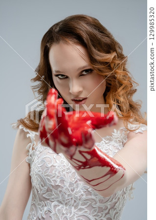Bride holding katana covered in blood, embodying dark beauty and fierce elegance 129985320