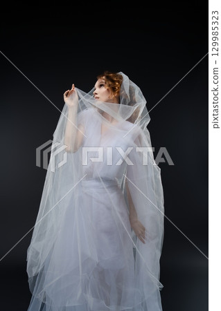 Beautiful woman dressed as a bride in elegant lingerie with soft veil 129985323