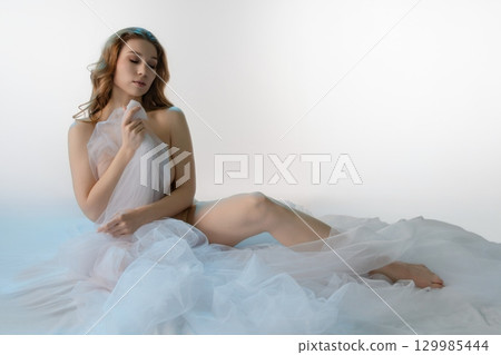 Sensual portrait of a woman draped in sheer fabric capturing beauty and elegance 129985444