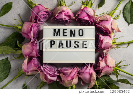 Word Menopause with pink flowers, flat lay, grey background 129985462