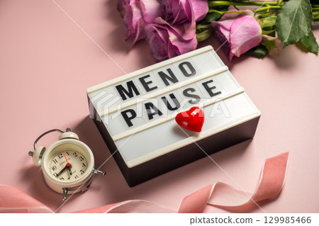 Word Menopause on light box with pink roses and alarm clock, flat lay, pink background Word Menopause on light box with pink roses and alarm clock, flat lay, pink background 129985466