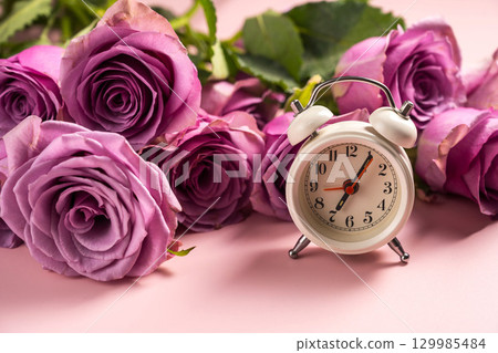 Alarm clock and pink roses. Time concept for women 129985484