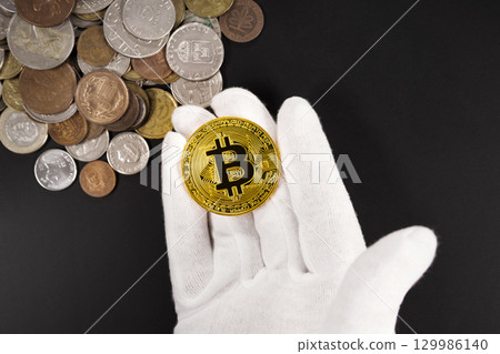 Hand holding Bitcoin over global currency coins Hand holding Bitcoin over global currency coins 129986140
