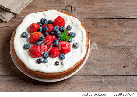 Sponge cake with whipped cream and fresh berries 129986767