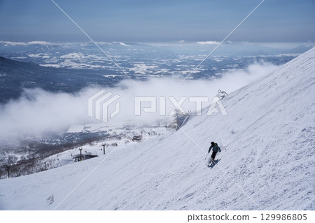 Skiers skiing from the dynamic course of Niseko Tokyu Grand Hirafu slope into the ski resort management area 129986805