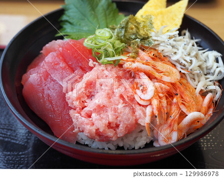 Bowl of rice topped with sashimi  129986978