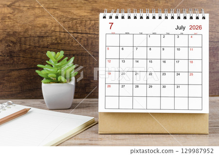 July 2026 desk calendar on the wooden worktable. 129987952