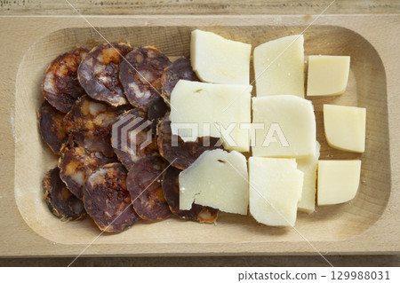 sliced salami and cheese cubes on wooden cutting board 129988031