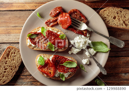 Ciabatta with sun dried tomatoes in olive oil, ricotta, and basil. 129988890