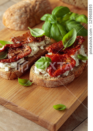 Ciabatta with sun dried tomatoes in olive oil, ricotta, and basil. 129988893