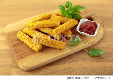 Cheese sticks with basil and ketchup on a wooden table. 129988894