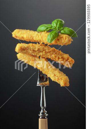 Cheese sticks with basil on a fork. 129988895