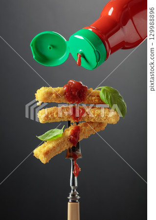 Cheese sticks with basil and ketchup on a fork. 129988896