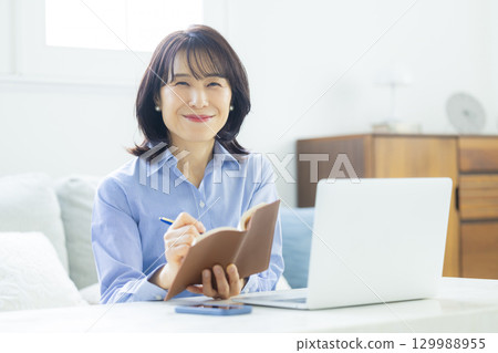 在客廳裡的中年女子遠程辦公 129988955