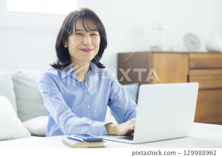 在客廳裡的中年女子遠程辦公 129988962