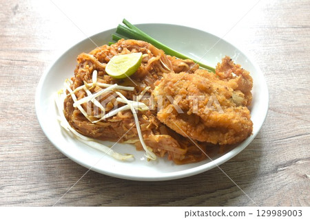 Pad Thai stir fried rice noodles with dry shrimp and egg topping crispy fried chicken on plate Pad Thai stir fried rice noodles with dry shrimp and egg topping crispy fried chicken on plate 129989003