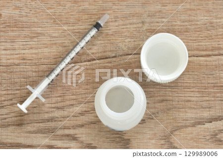 bottle opened cap of potion liquid drug with syringe medical equipment arranging on table 129989006