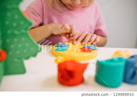 A child creating colorful designs with play dough at home in a cheerful indoor setting 129989010
