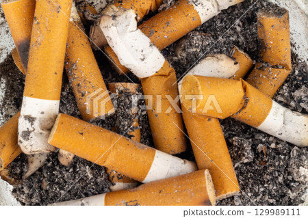 Closeup of cigarette butt and ashes on a plain background 129989111