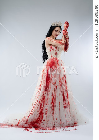Bridal beauty wielding a knife with blood splatters in a haunting setting 129989280